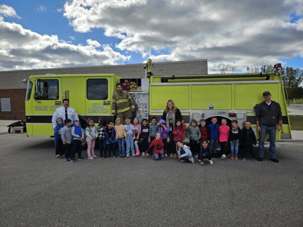 Group of children with adults in front of firetruck