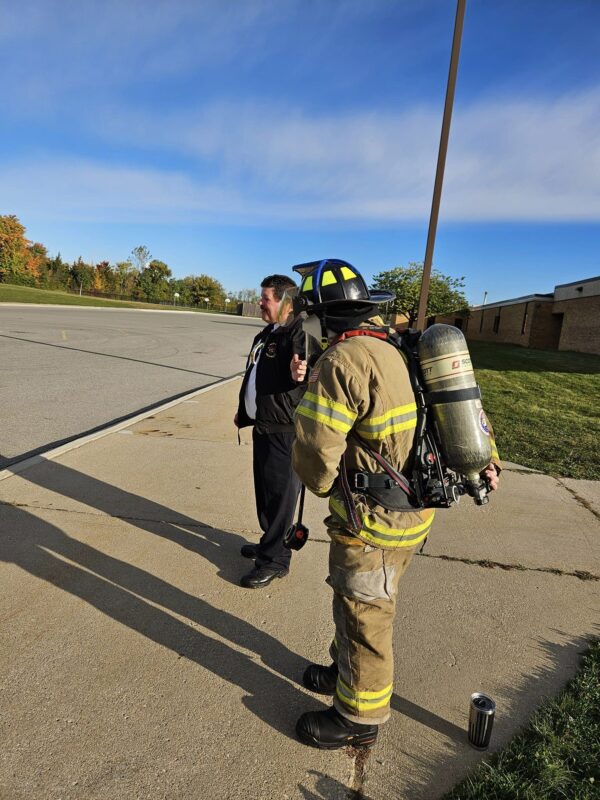 Firefighter in gear talking with colleague outdoors