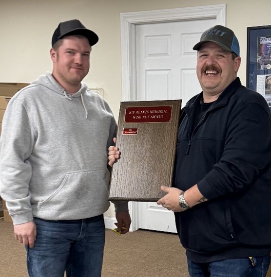 Two men smiling, holding a memorial award plaque